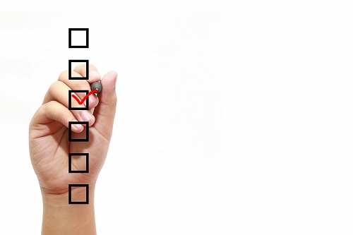 Businessman checking mark on checklist with marker over white