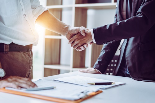 Middle age Asian partner lawyers attorneys shaking hands after discussing a contract agreement done.